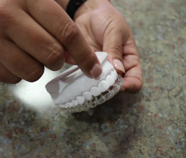 Dental professional holding a clear aligner over a dental model