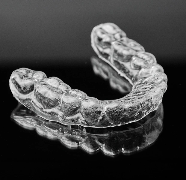 Clear dental night guard shown on a dark background